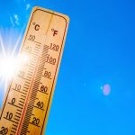 Summer background - blue sky with bright sun and thermometer