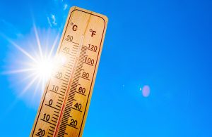 Summer background - blue sky with bright sun and thermometer